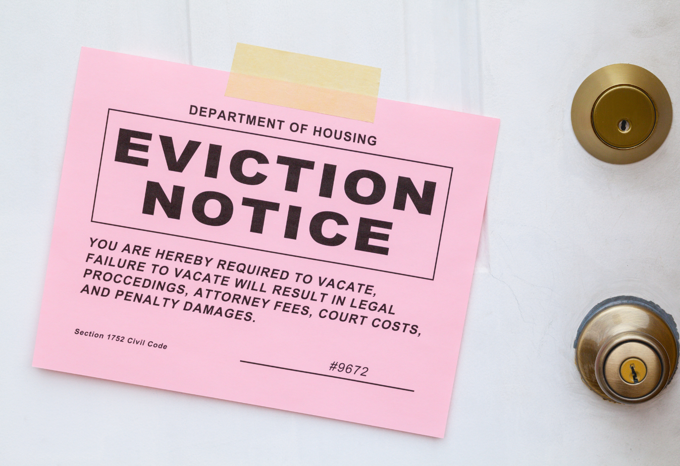 a pink eviction notice taped to a white door with bronze knob and top lock