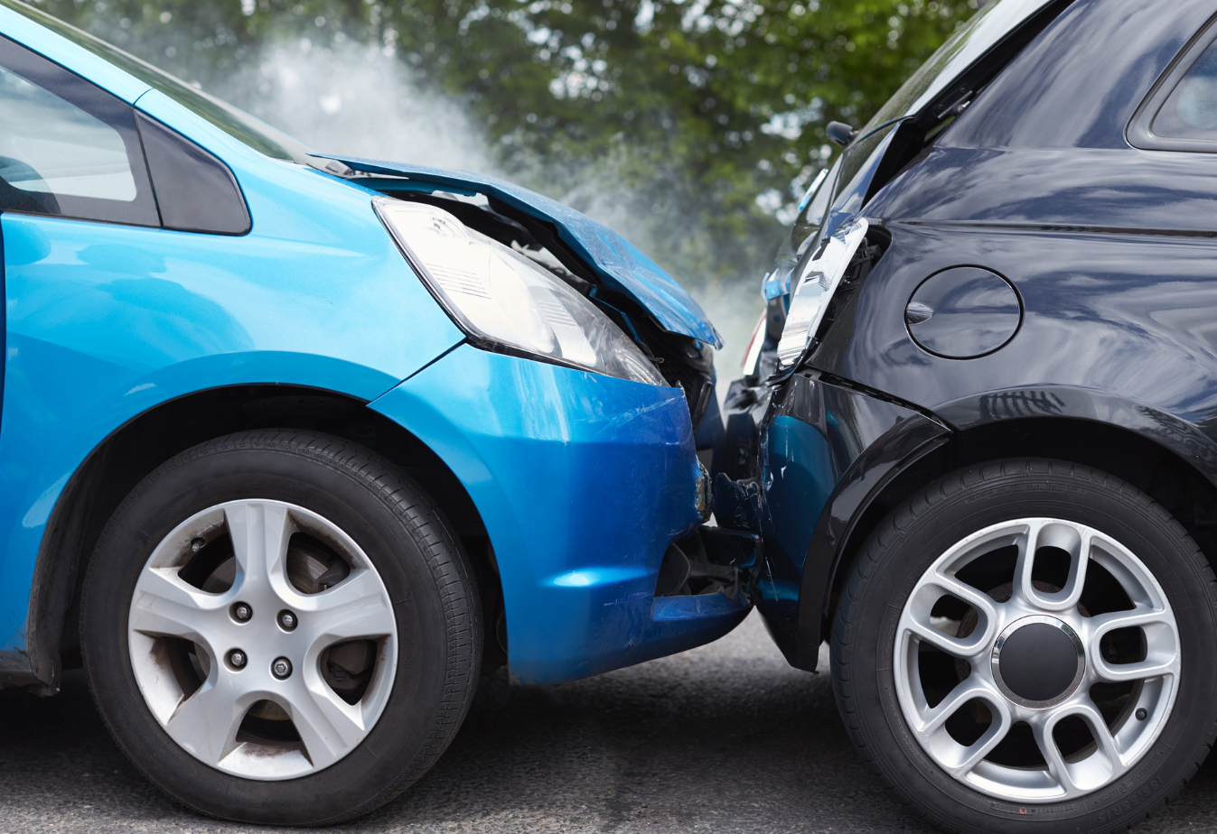 a bright blue car rear ended a black car and smoke is rising from the hood