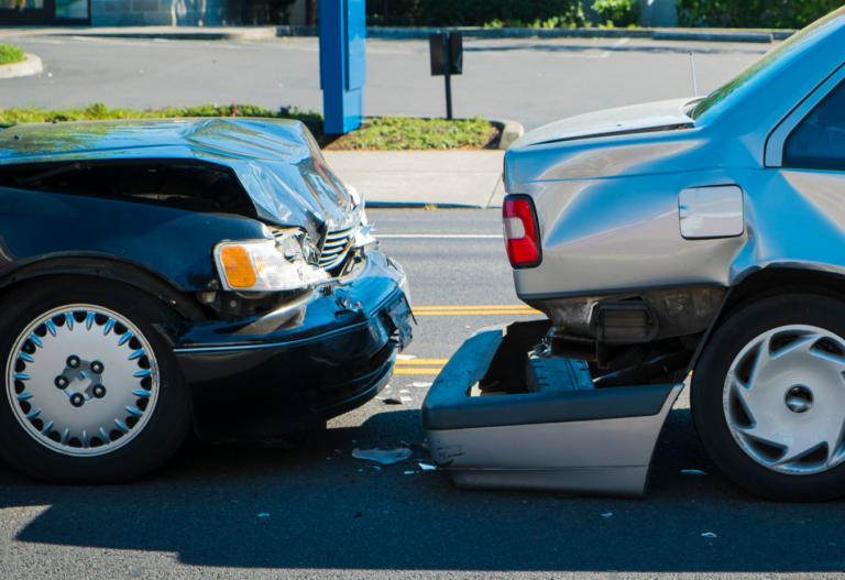 fender bender between a black car that hit a silver car and the silver car's bumper has fallen off