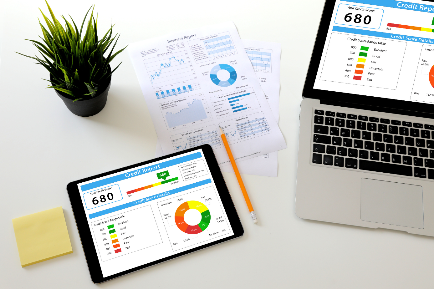 overhead photo of tablet and laptop with various credit scores and data