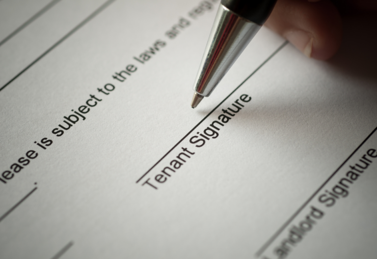 the point of a pen hovering over a document line that reads "tenant signature"