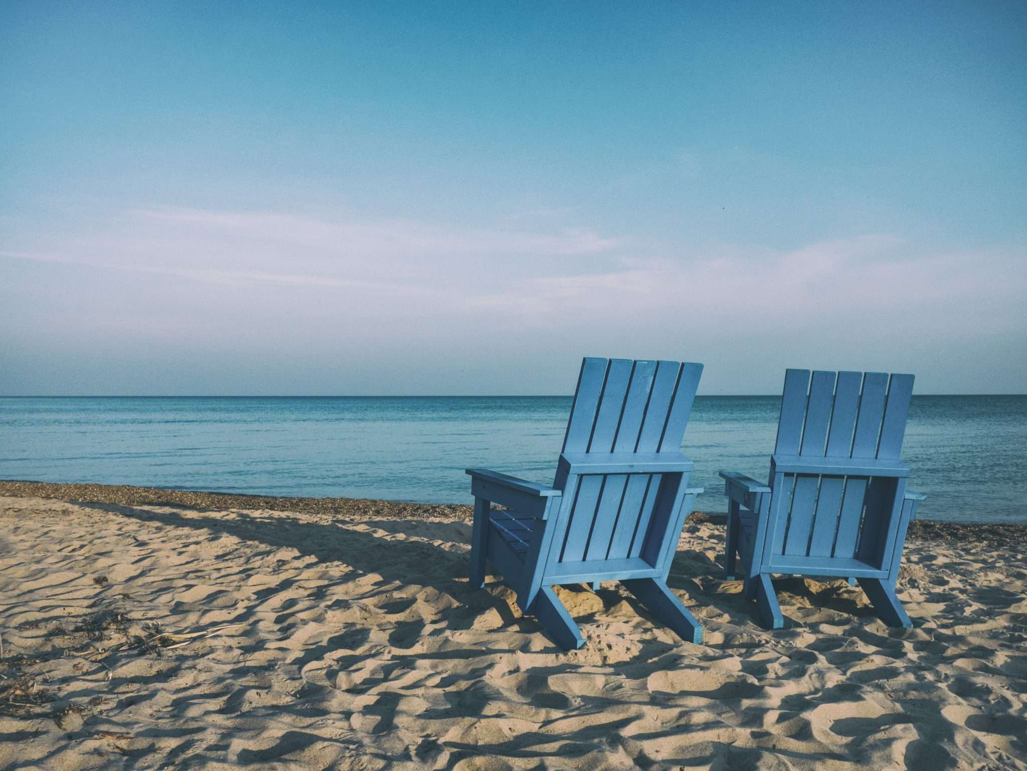 beach with two blue beach chairs facing the ocean