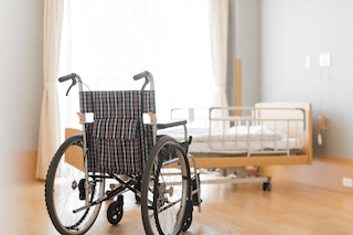 wheelchair in a nursing home with a bed in the background