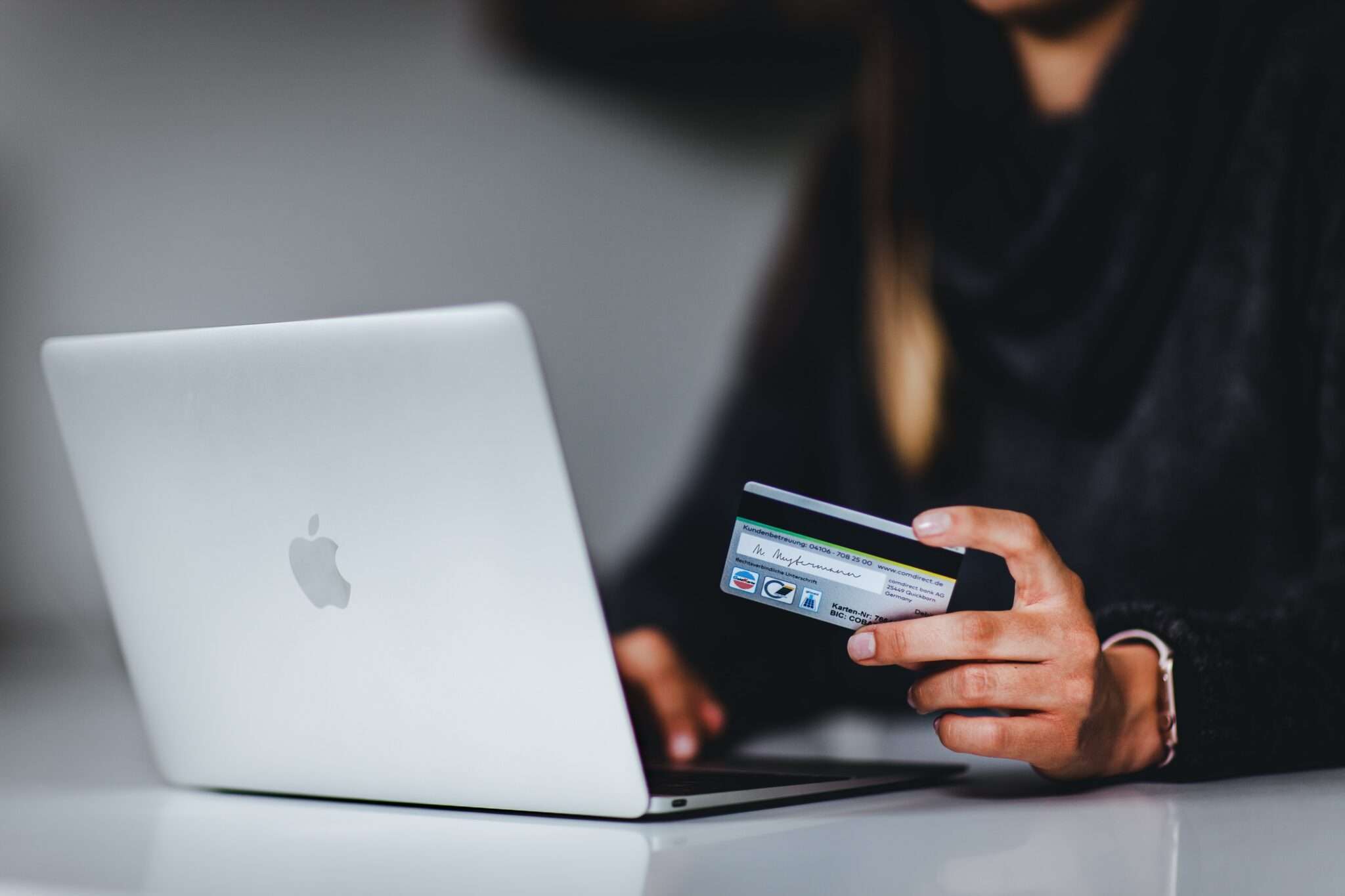 person holding a credit card in front of a laptop