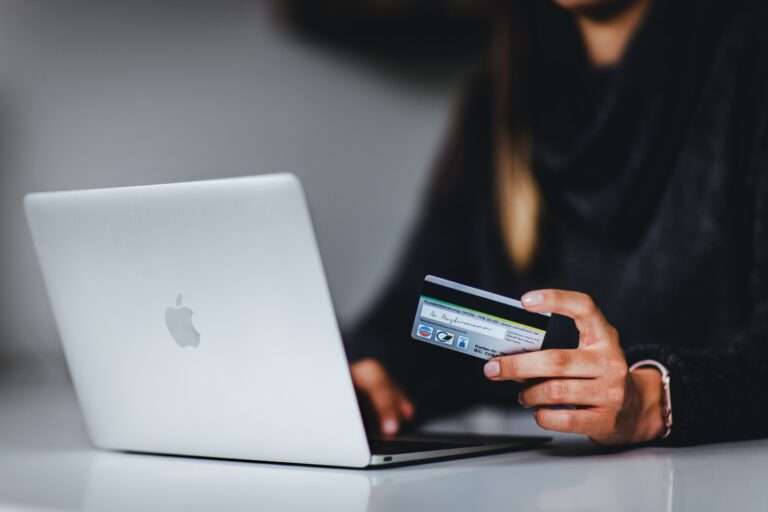person holding a credit card in front of a laptop