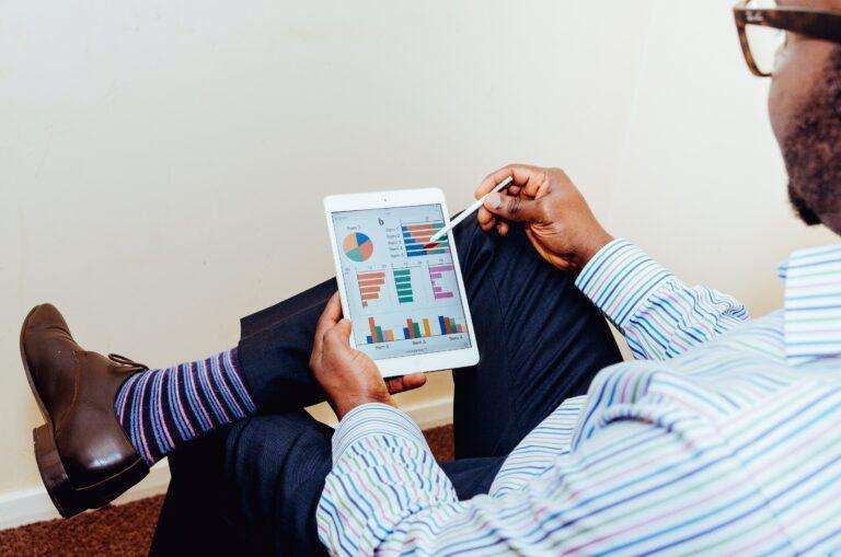 a man holding a small tablet with charts and graphs