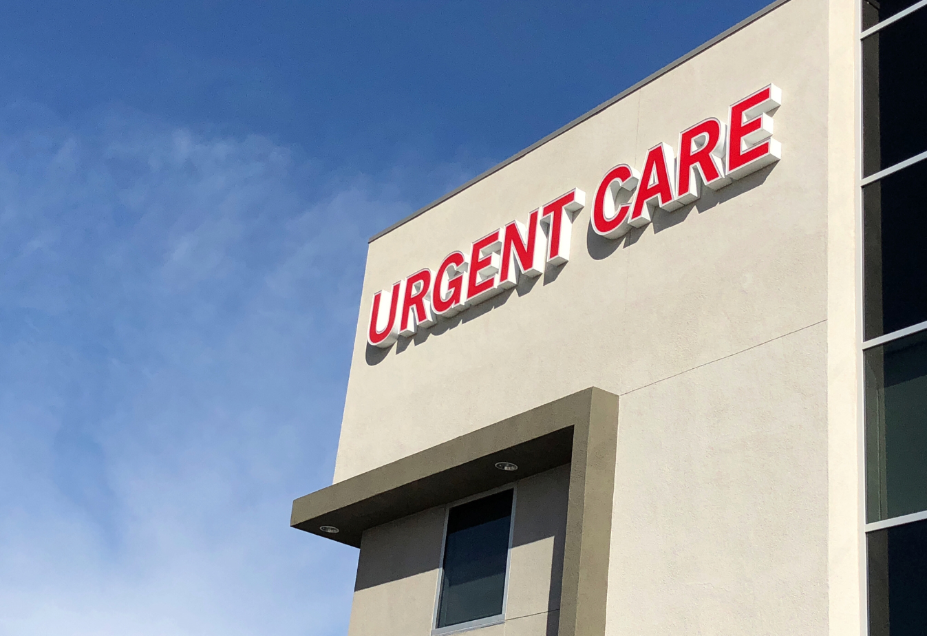 Outside view of a building with an Urgent Care sign against a blue sky with few clouds